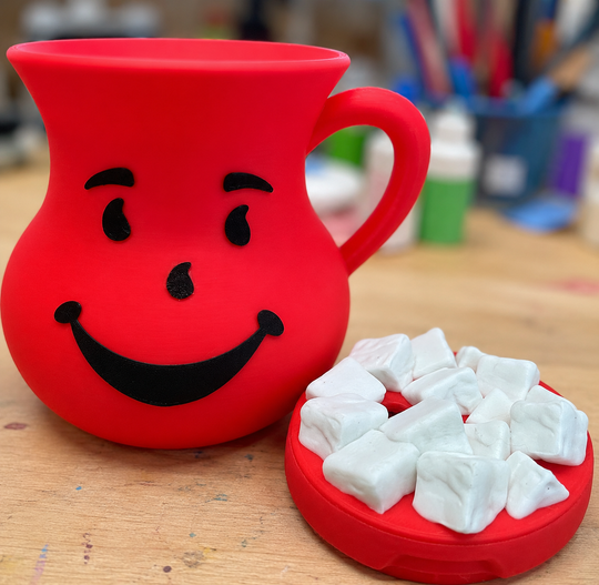 Red mug with a smiley face design and a container of white cubes on a wooden surface.