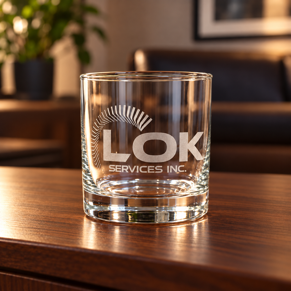 Single LOK Services engraved whiskey glass on walnut sideboard